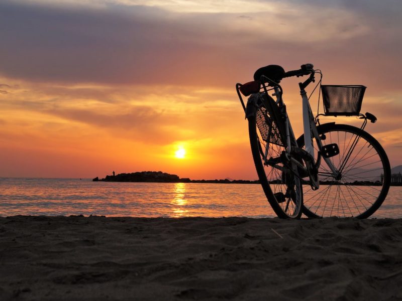 Un vélo posé sur une plage de la presqu'île du Cap Ferret au coucher du soleil.